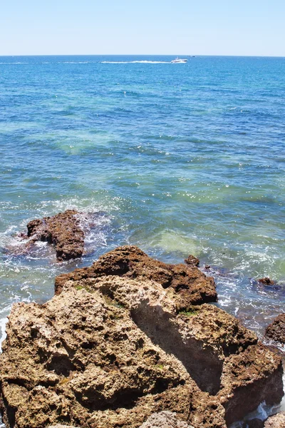 Powerboat on the horizon in the sea near the rocks. — Stock Photo, Image