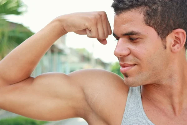 Jonge man pronken biceps spieren Rechtenvrije Stockafbeeldingen