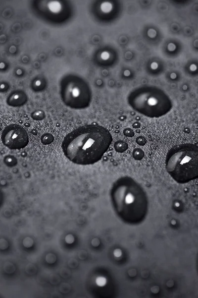 Efeito de lótus com gotas de água em têxteis pretos — Fotografia de Stock