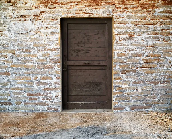 Oude houten deur op bakstenen muur — Stockfoto