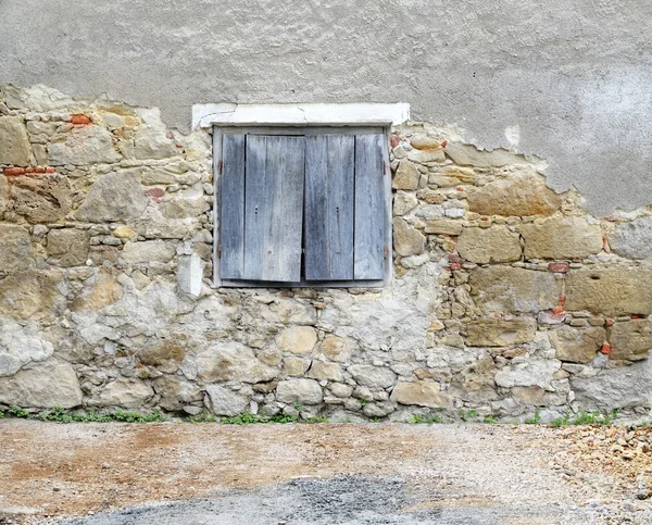 Steinmauer mit hölzernen Fensterläden — Stockfoto
