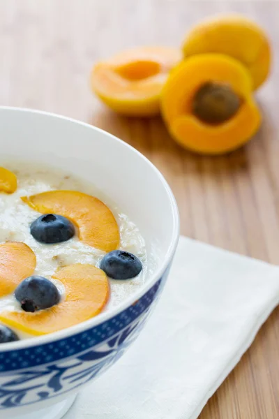 Oatmeal porridge with fresh berries and apricots — Stock Photo, Image