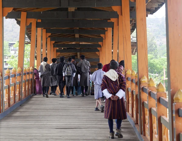 Bhutanese walk across the bridge of the Punakha Dzong (Bhutan) — Stock Photo, Image