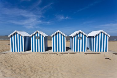 White and blue striped beach house on a sunny beach in France clipart