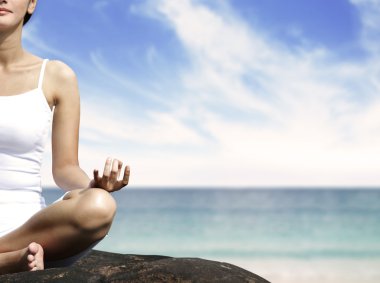 Woman meditating on a rock clipart