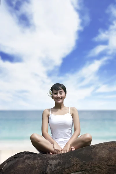 Uśmiechnięta kobieta siedzi na skale — Zdjęcie stockowe