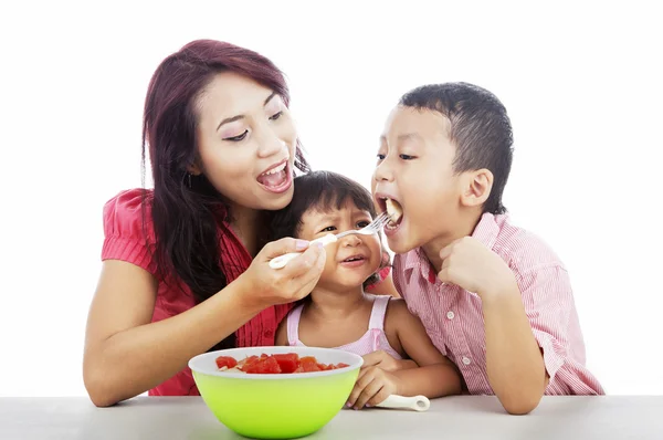 Mutter und Kinder essen Obstsalat — Stockfoto