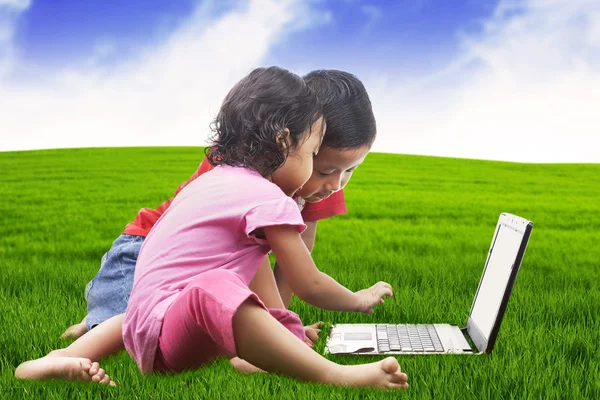 Asiatische Geschwister mit Laptop im Freien — Stockfoto