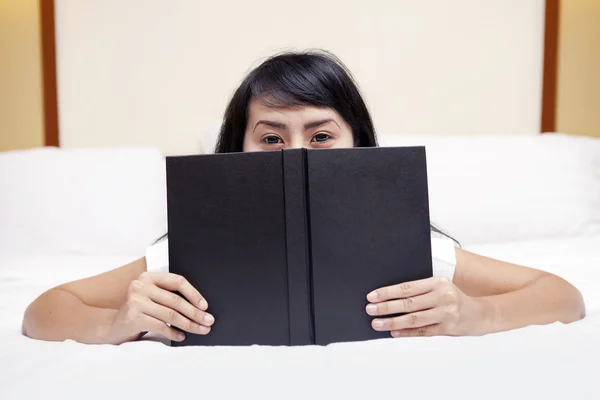 Kvinna kikar bakom boken — Stockfoto