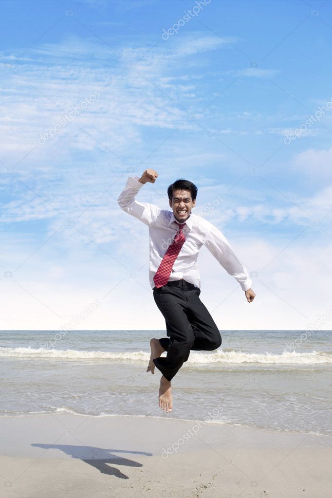 Success bussinessman jumps at beach