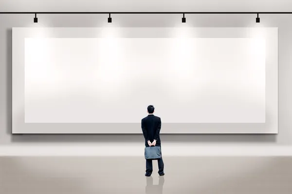 Geschäftsmann blickt auf eine leere Plakatwand — Stockfoto