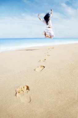 Woman with footprint enjoying freedom on beach clipart