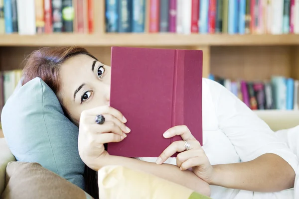 Woman looking from behind book — Stock Photo, Image