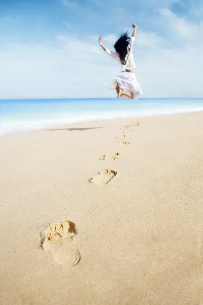 Kvinna med fotavtryck njuter frihet på stranden — Stockfoto