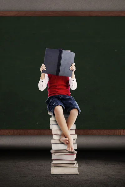 Asiático niño leyendo un libro en pila de libros — Foto de Stock