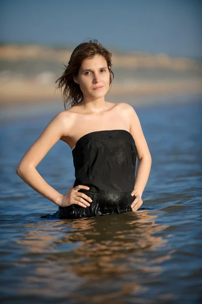 Femme en robe noire à la plage se mouiller — Photo