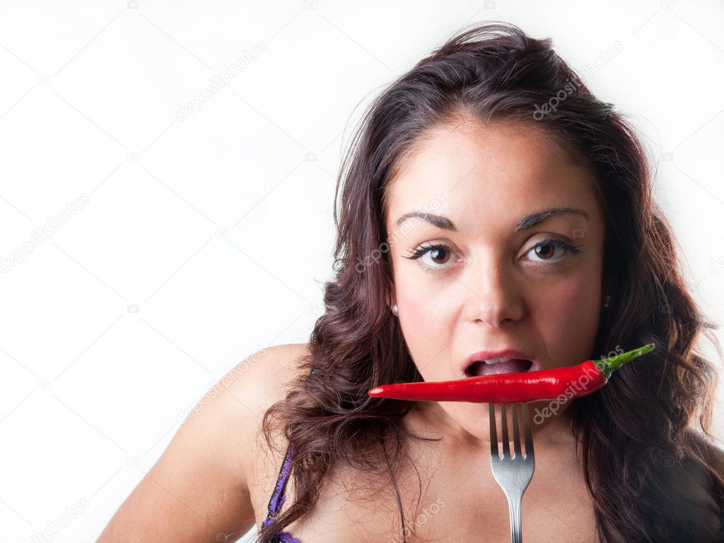 Brunette woman biting a chilli