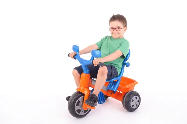 Giovane ragazzo cavalcando il suo triciclo — Foto Stock