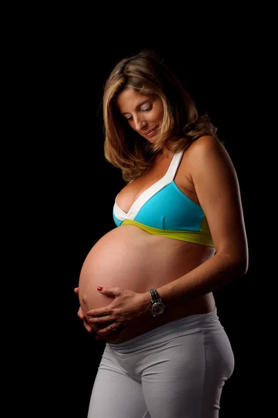 妊娠中の女性は彼女の腹を見て — Stockfoto