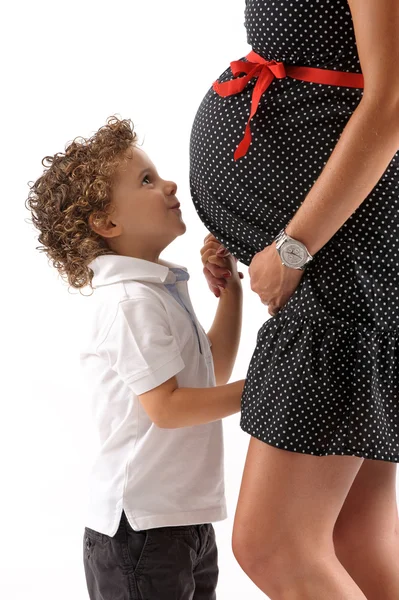Preganat woman with a kid lookink at her belly — Stock Photo, Image