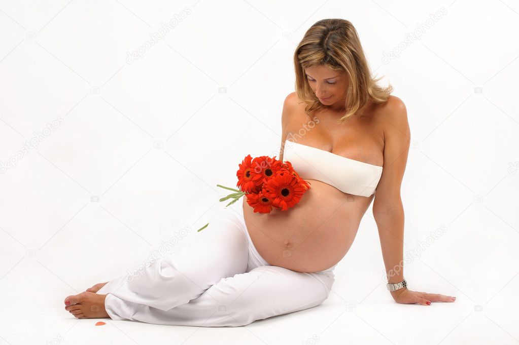 Pregnant woman seated on the floor with red flowers