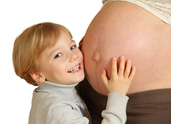 Маленький мальчик обнимает живот беременной матери — стоковое фото