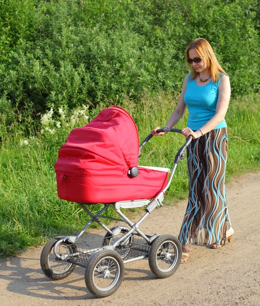 Forty-year mother walks with a baby carriage — Stock Photo, Image