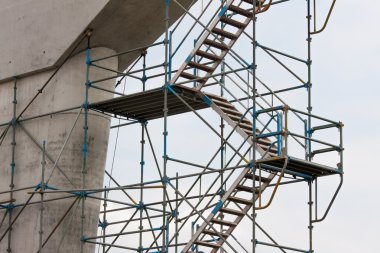 Scaffolding on a construction site, against a clear sky. clipart