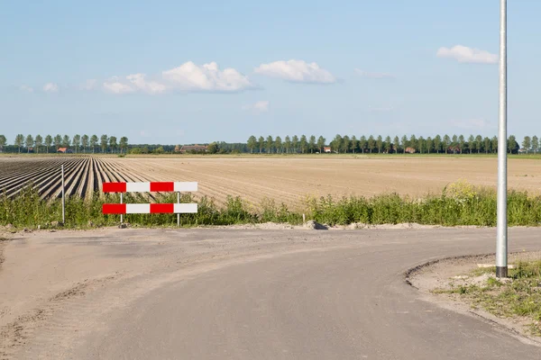 Jalan dengan tanda lalu lintas dekat lahan pertanian telanjang — Stok Foto