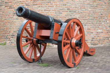 Old medieval artillery canon before a brick wall clipart