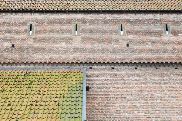 Старая городская стена из кирпича и две крыши с черепицей — стоковое фото