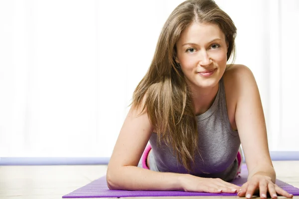 Atractiva joven mujer acostada en su esterilla de yoga —  Fotos de Stock