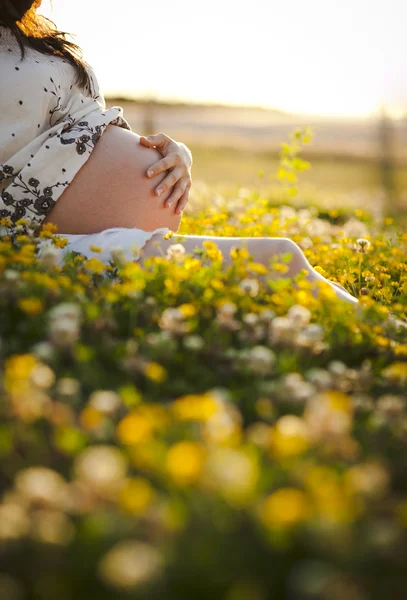 Kobieta w ciąży siedzieć na trawie — Zdjęcie stockowe