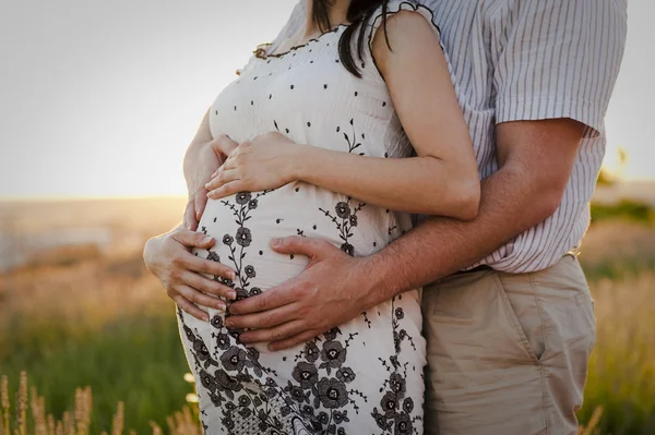 Пара обнимает беременный живот — стоковое фото