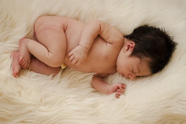 Pequeño recién nacido soñando en una alfombra de pelo —  Fotos de Stock