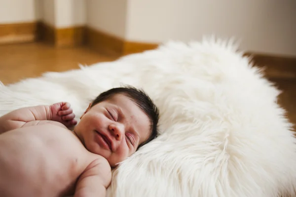 Smiling newborn on a hair white blanket — Stock Photo, Image
