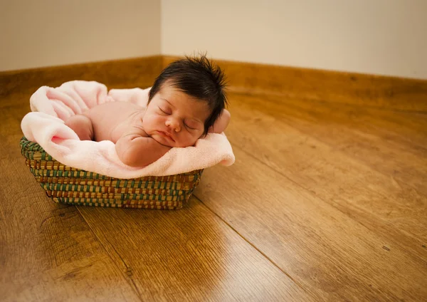 Nyfödd naken sovande på en korg Royaltyfria Stockbilder