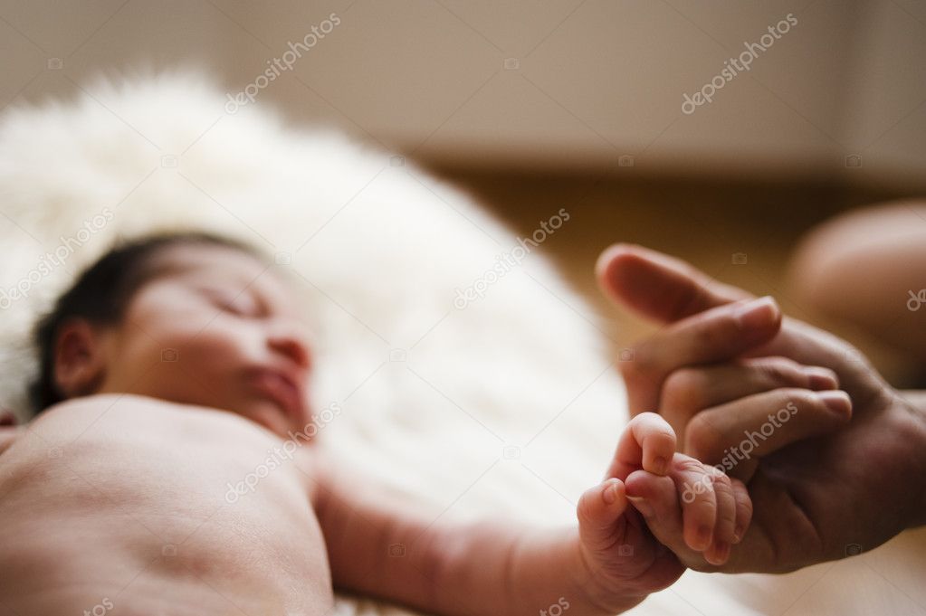 Newborn catching the finger of her mom