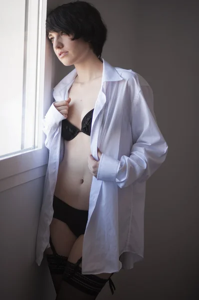 Sexig brunnette tjej tittar bort vid fönstret i underkläder — Stockfoto