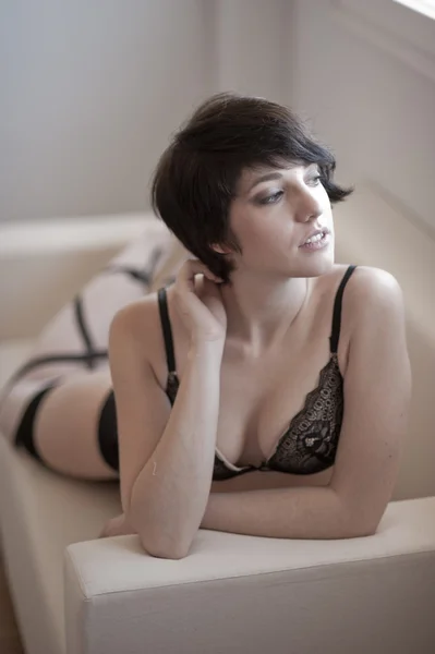 Сексуальная брюнетка, смотрящая в белье на диван — стоковое фото