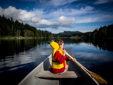 Child canoeing on lake clipart