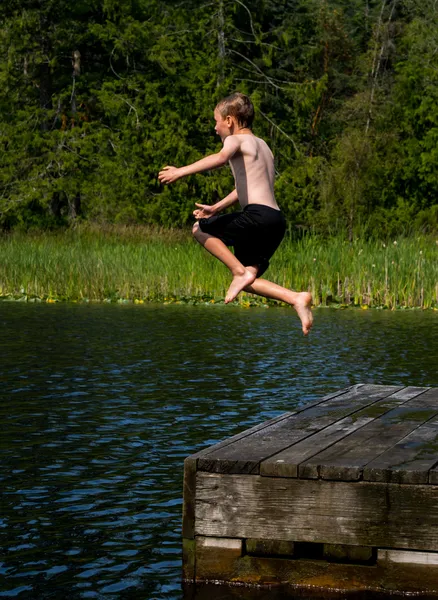 Rapaz a correr da doca para o lago — Fotografia de Stock
