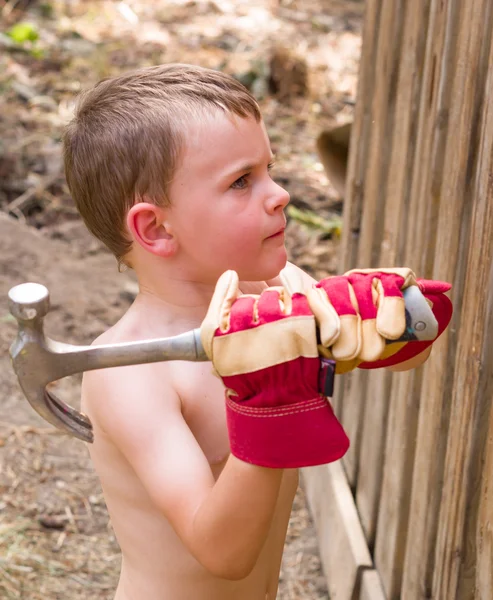 Chlapec pomáhá kladivem hřebíky — Stock fotografie