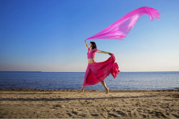 Vacker flicka som hoppa på stranden vid solnedgången — Stockfoto