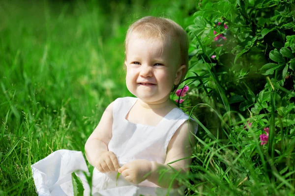 Pequena menina bonita em um gramado verde — Fotografia de Stock