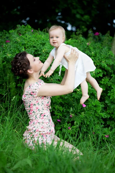 Маленький милый малыш на зеленой лужайке с мамой — стоковое фото