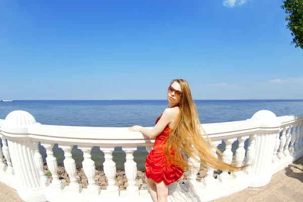 Mädchen im roten Kleid am Strand — Stockfoto