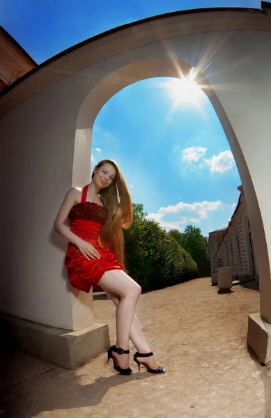 Luxe meisje in een rode jurk tegen de zon — Stockfoto