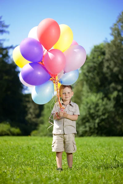 Ñhild with a bunch of balloons in their hands — ストック写真