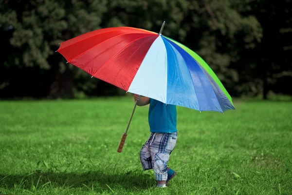 Liten pojke med en stor regnbåge paraply — Stockfoto
